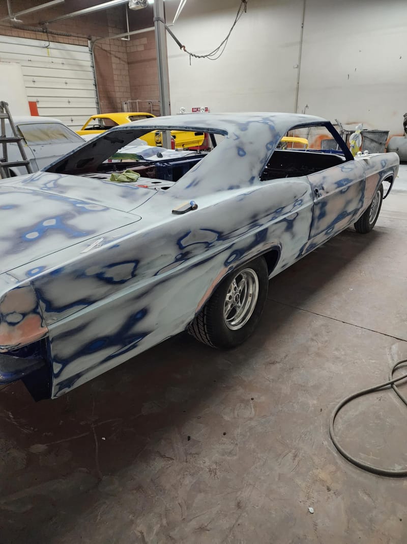 The same classic coupe in bare bodywork with blue guide coat across the panels, before paint