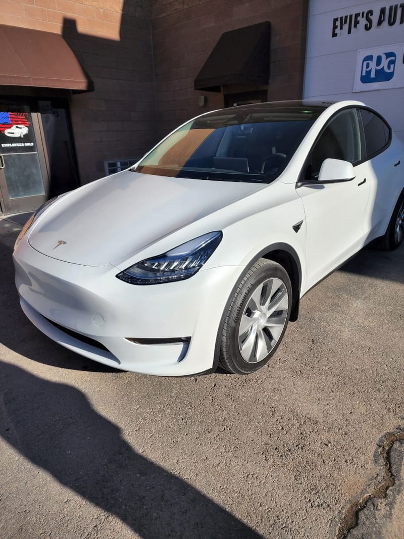 The finished white Model Y outside the shop, front corner clean and the panel gaps even