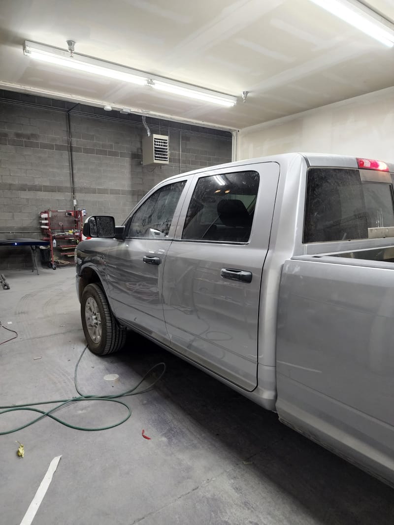 The finished silver Ram 3500 crew cab back together in the shop, doors hung and panels aligned