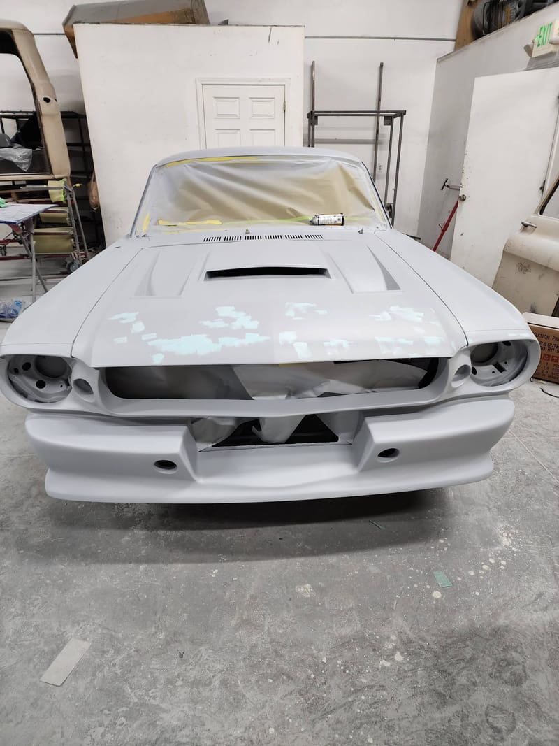 The front end of a classic Mustang in uniform grey primer, masked and ready for paint