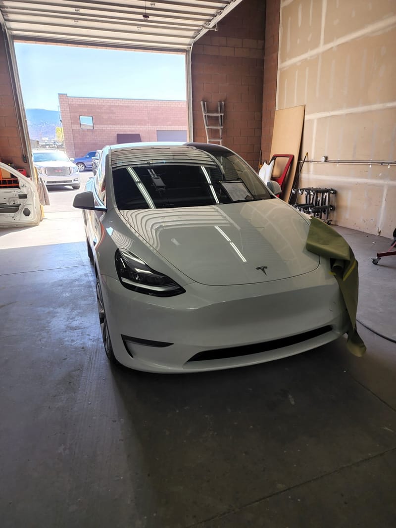The Model Y inside the bay with its front corner masked off in paper and tape