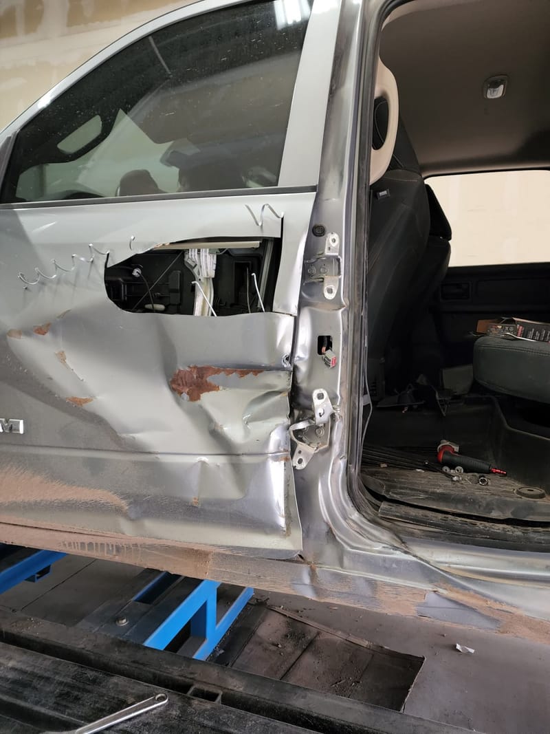 Close-up of the same truck: the door opening torn open, sheet metal folded back and the hinge pillar bent