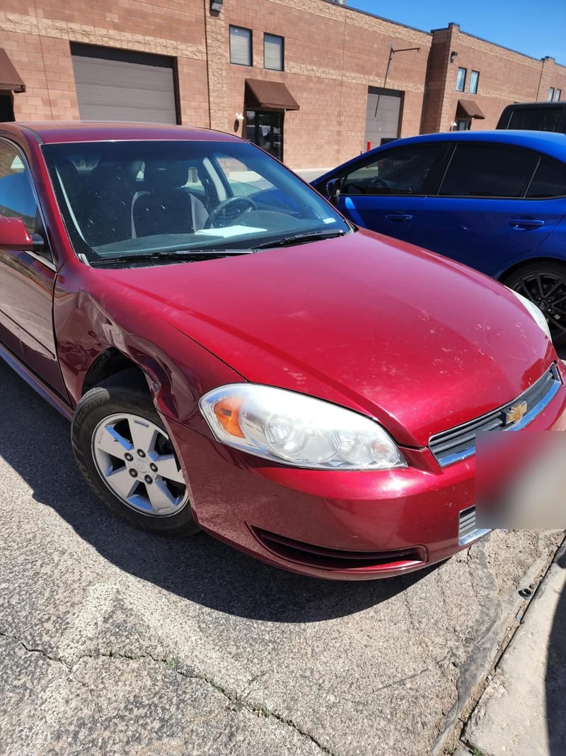 A dark red Chevrolet Impala with a long crease pushed into the front fender and door