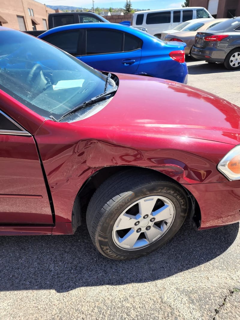 Close-up of the crease along the Impala front fender, the metal pushed in and the paint broken